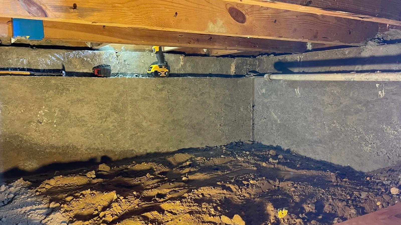 Crawl space with newly sealed concrete foundation walls and dirt floor.