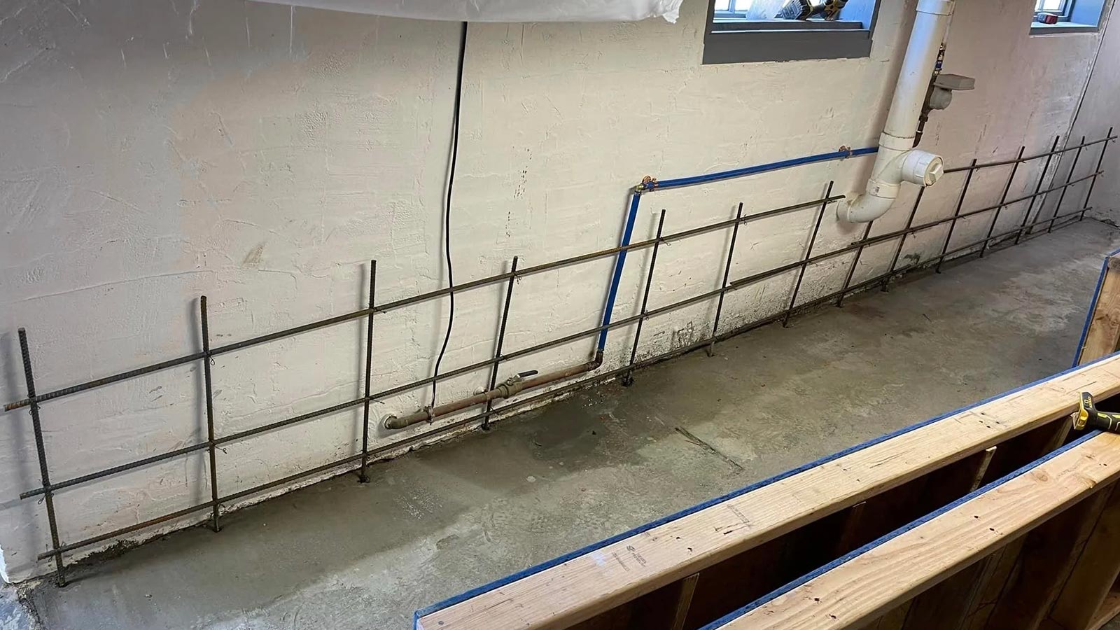 Basement floor with rebar installation and freshly poured concrete.