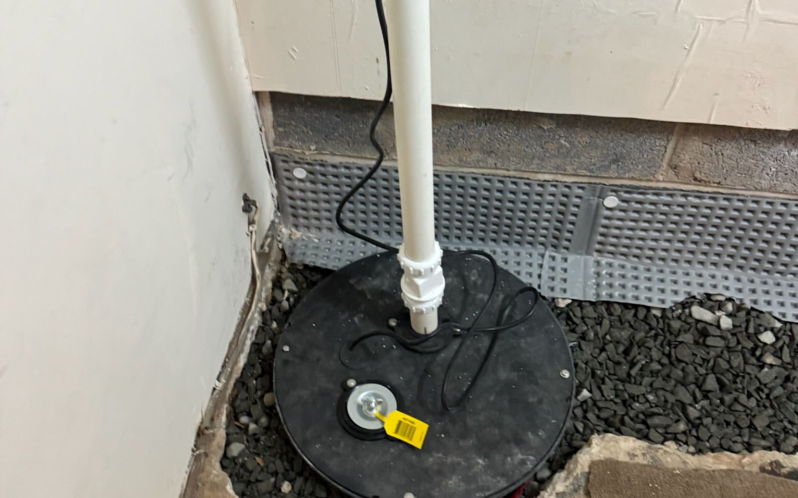 Sump pump system installed with discharge pipe in a basement waterproofing setup.