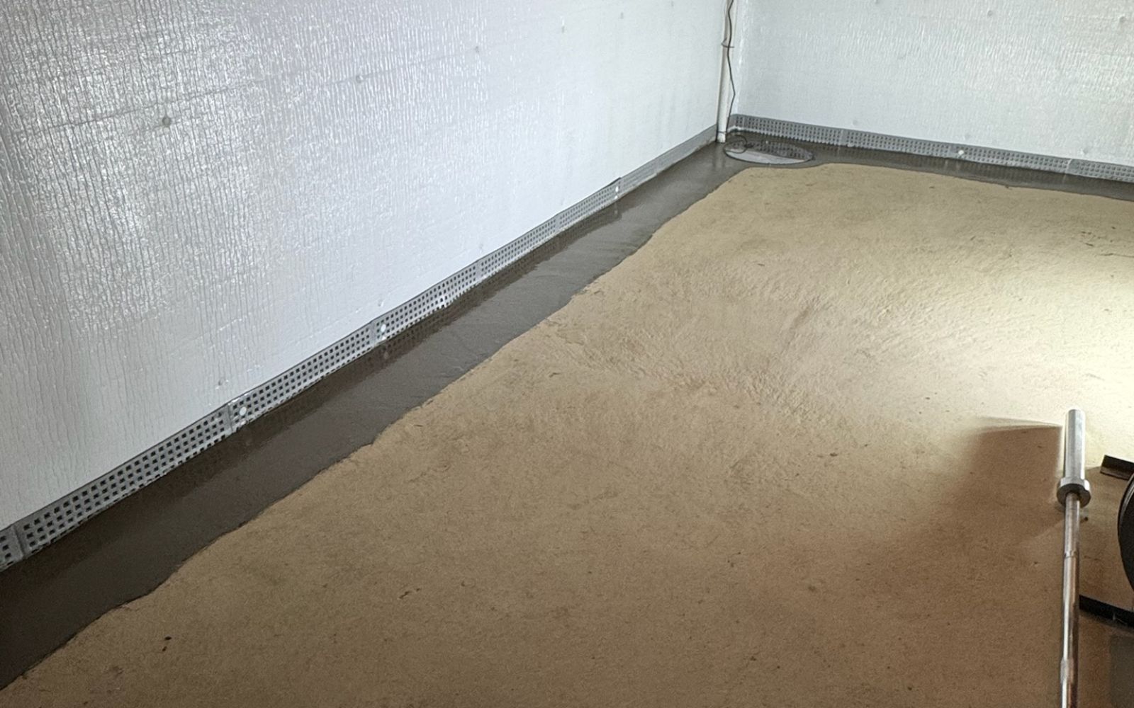 user-inserted A basement with a waterproofing system, including a concrete floor, drainage channel, and vapor barrier on the walls.