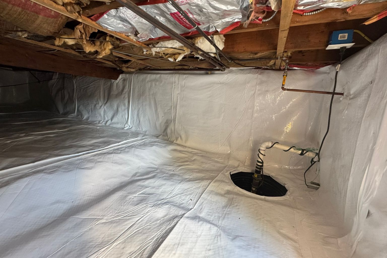 Installed vapor barrier in a crawl space with a sump pump, providing moisture control and protection against mold, water damage, and air quality issues. Learn how a sealed crawl space can improve your home's health and energy efficiency.