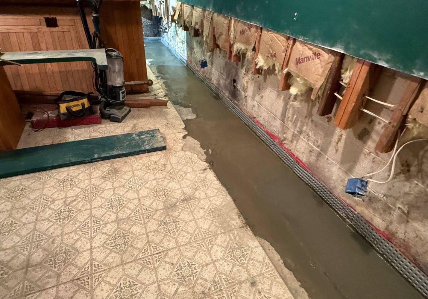 Basement floor waterproofing in progress with concrete pouring and wall liner installation.